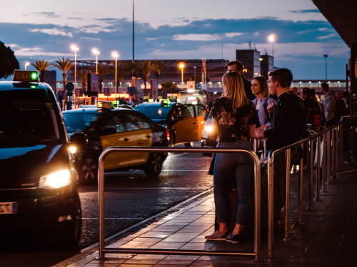 Colorful dusk with Tourists and visitors of Barcelona waiting for the taxi car in queue in front of the El Prat Barcelona international airport