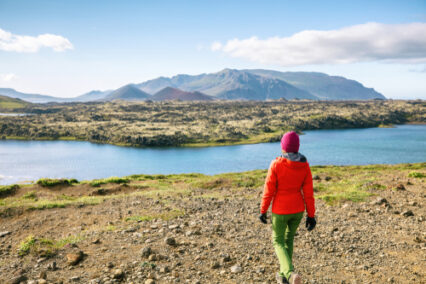Hiker girl walking across lava fields in amazing dramatic Icelandic landscape.