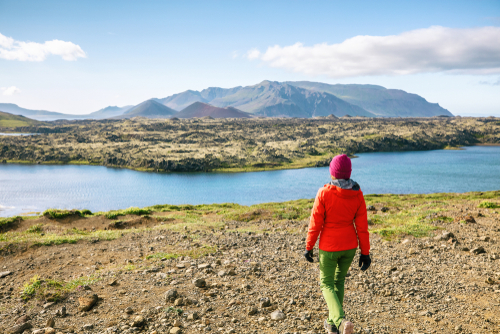 Hiker girl walking across lava fields in amazing dramatic Icelandic landscape.