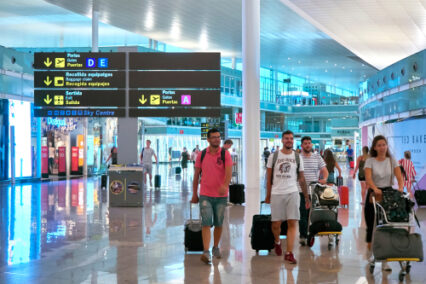 Passengers in transit in a Terminal of Barcelona international airport with a Dutyfree stores in background. Barcelona, Catalonia, Spain.