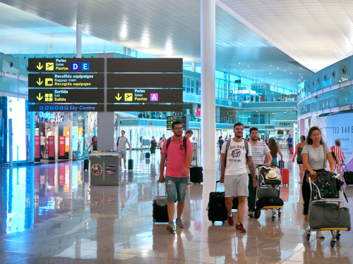 Passengers in transit in a Terminal of Barcelona international airport with a Dutyfree stores in background. Barcelona, Catalonia, Spain.