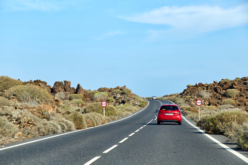 Landscape with road and red car at Lanzarote Island, Canaries, Spain