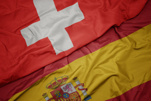Waving colourful flag of Spain and national flag of Switzerland.