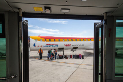 baggage unloading from a landing plane, view from airport bus