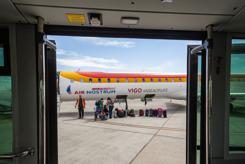 baggage unloading from a landing plane, view from airport bus