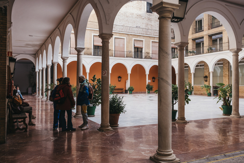 Courtyard of University of Seville, one of the top-ranked universities in Spain with a group of students talking inside.