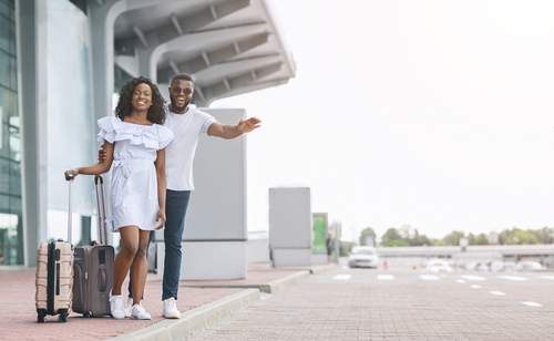 ransfer From Airport. Young Couple Catching Taxi On Parking Near Terminal