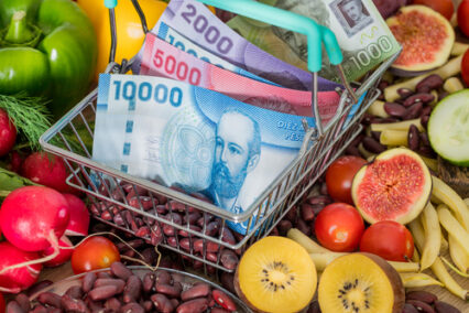 Shopping basket with Chile money, around food products, vegetables and fruits.