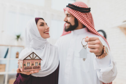 A man looks at his wife and holds the keys to a new apartment in his hands.