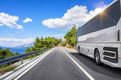 White passenger bus on the highway against the backdrop of a beautiful landscape.