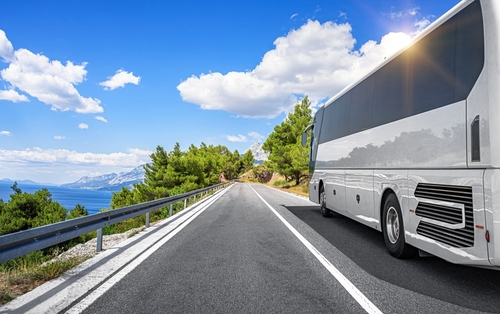 White passenger bus on the highway against the backdrop of a beautiful landscape.