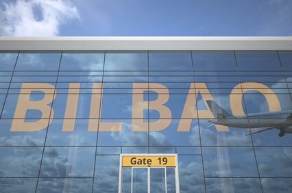 Airliner reflecting in the windows of airport terminal with Bilbao text 3D rendering