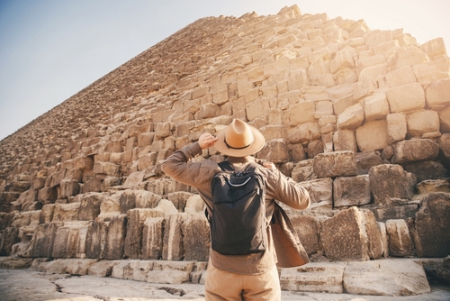 Man tourist walks background of pyramids in Giza Cairo Egypt, sun light.