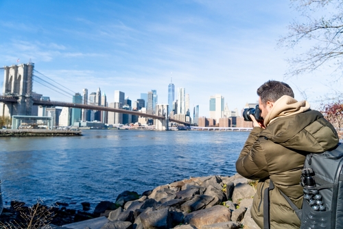New York city man taking pictures of manhattan view from brooklyn park