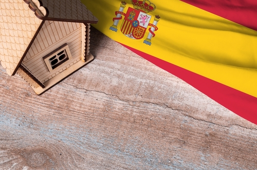 House real estate model near Spain flag.