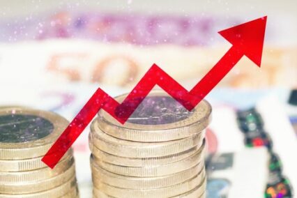 Red arrow over banknotes and euro coins, concept of increase of cost of living.