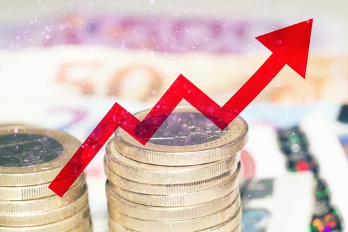 Red arrow over banknotes and euro coins, concept of increase of cost of living.