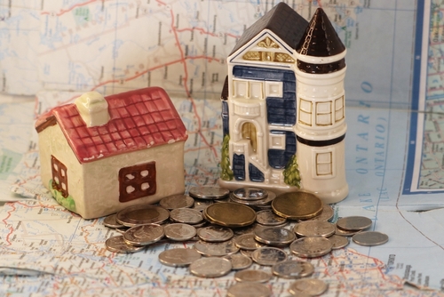 Two figurine houses atop a map of Ontario with Canadian change.