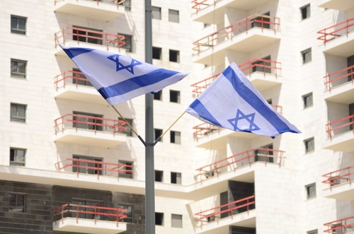 Modern apartment buildings and the flag of Israel.