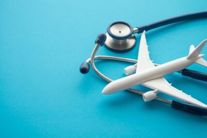 Airplane and stethoscope on blue background with copy space.