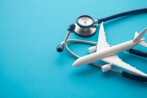 Airplane and stethoscope on blue background with copy space.