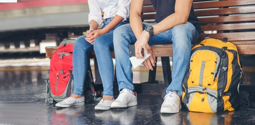 Young Traveler man and woman wearing sneaker and sitting at train station.