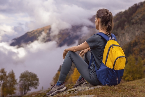 Woman tourist traveler sit on the top of mountain, solo travel in mountain