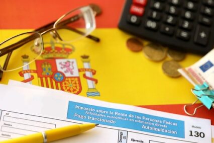 Modelo 130 spanish tax form for personal income tax for employers and professionals in direct evaluation instalments lies on flag of Spain close up on accountant table