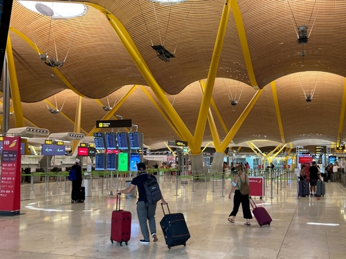 People carrying luggage in the Barajas Adolfo Suarez International Airport in Madrid during the summer vacation. Spain.