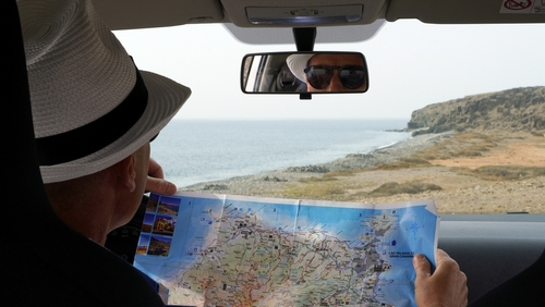 Tourist in rental car looks at the map while driving on the coast.