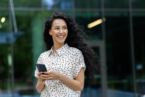 Woman smiling and holding a cell phone.
