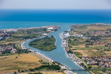 Aerial view of the city of Fiumicino near Rome airport, with historic ancient site of Ostia Antica Roman ruin excavations and the river Tiber flowing out to the Mediterranean Sea in summer sunshine