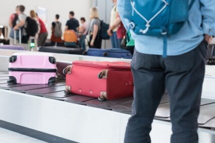 Passengers waiting at the airport baggage claim area for their luggage to arrive after a flight