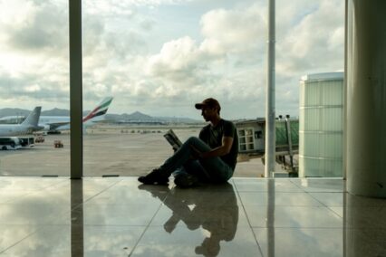 Young adult reading a travel guide while waiting for his plane at the airport
