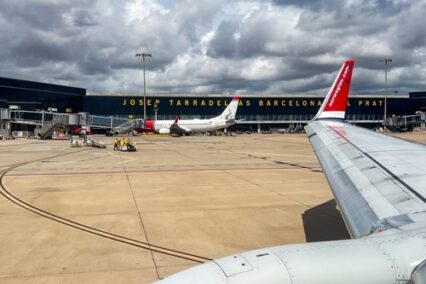 Airplane wing at Josep Tarradella Barcelona-El Prat Airport, ready for takeoff under a cloudy sky