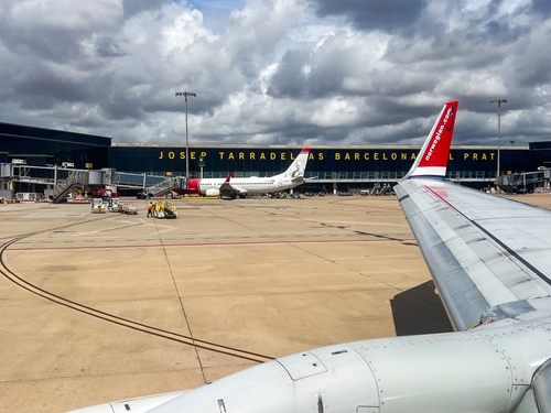 Airplane wing at Josep Tarradella Barcelona-El Prat Airport, ready for takeoff under a cloudy sky