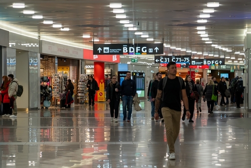Airport terminal interior. Boarding gate signs. Passengers walking through the terminal.