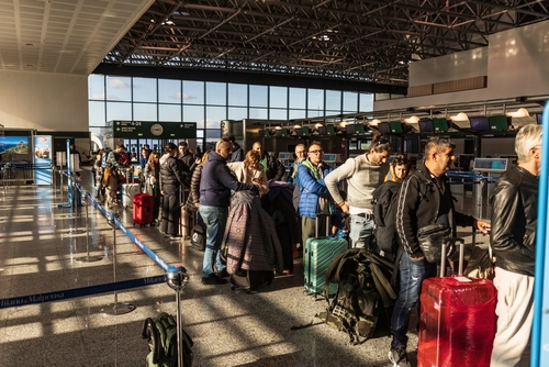 Airport passengers in a queue with their baggage in Milan