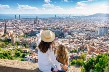 A tourist shows his daughter the panoramic view of the Barcelona skyline on a sunny day