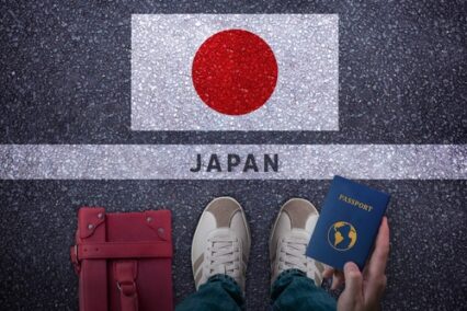 Traveler perspective with bag, passport and Japan flag on asphalt road