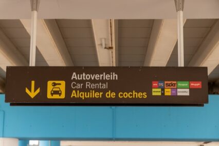 Airport car rental sign displays multilingual options and brand logos guiding travellers to transportation services available in Malaga, Spain