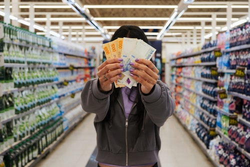 girl holding Argentine peso bills in the supermarket.