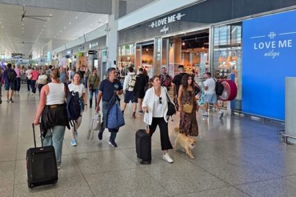 Travelers walking past shops and cafes inside the busy airport terminal at Málaga Airport, Málaga, Andalusia, Spain