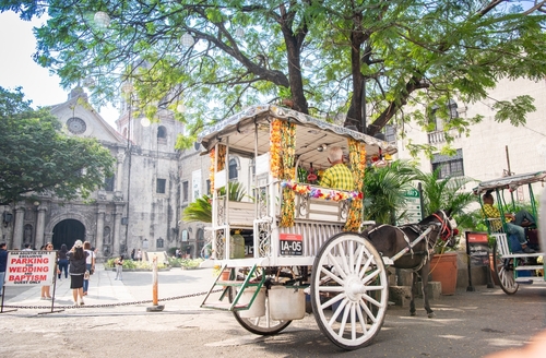 Traditional Kalesa horse carriage with San Agustin Church background in Intramuros Manila Philippines