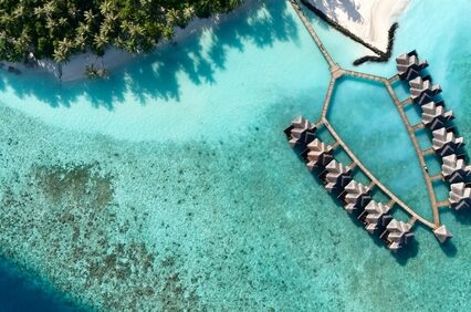 Aerial view of a tropical luxury resort in the Maldives with overwater villas surrounded by crystal clear turquoise lagoon - an idyllic island getaway