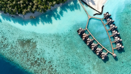 Aerial view of a tropical luxury resort in the Maldives with overwater villas surrounded by crystal clear turquoise lagoon - an idyllic island getaway