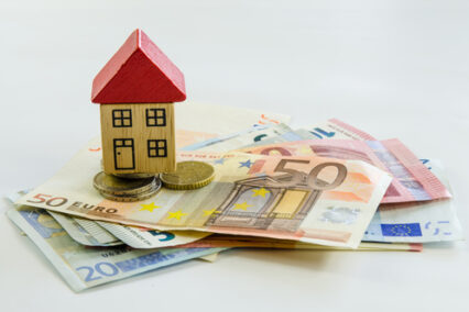 Wooden toy house, banknotes and coins