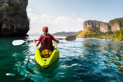 Lady paddling kayak in the calm tropical bay