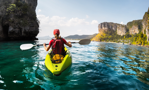 Lady paddling kayak in the calm tropical bay