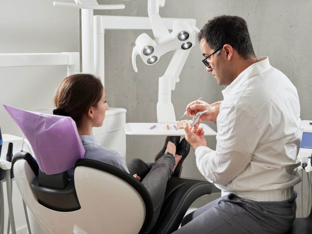 Un dentiste avec une patiente allongée sur le fauteuil dentaire